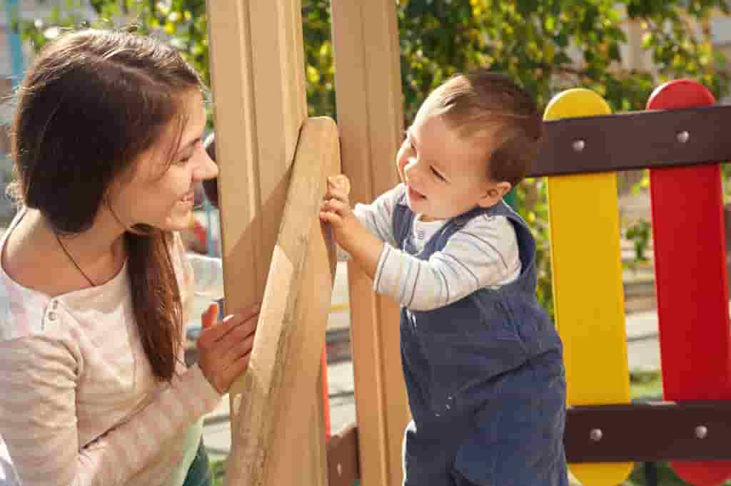 nanny playing with toddler boy in playground